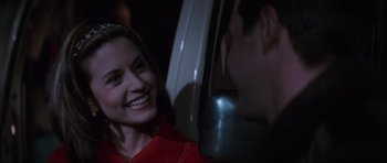 Movie still from “Scream” (1996), directed by Wes Craven – A woman smiling at a man in a red shirt; Close Up shot, Over the shoulder angle