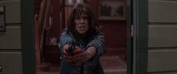 Movie still from “Scream” (1996), directed by Wes Craven – A woman with blood on her face holding a gun; Medium shot, Low angle
