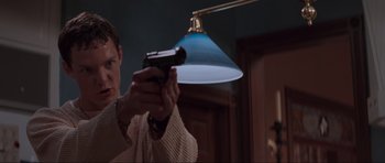 Movie still from “Scream” (1996), directed by Wes Craven – A man holding a gun in front of a lamp; Medium shot, Low angle