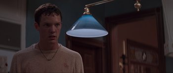 Movie still from “Scream” (1996), directed by Wes Craven – A man standing in front of a lamp in a room; Close Up shot, Low angle