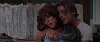 Movie still from “Scream” (1996), directed by Wes Craven – A young woman holding a knife with blood on her face; Medium shot, Low angle