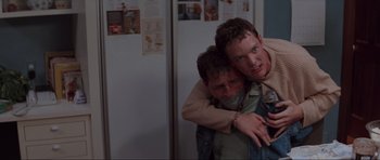 Movie still from “Scream” (1996), directed by Wes Craven – A couple of men hugging each other in a kitchen; Medium shot, Low angle