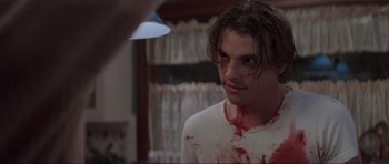 Movie still from “Scream” (1996), directed by Wes Craven – A young man with blood all over his face; Close Up shot, Over the shoulder angle