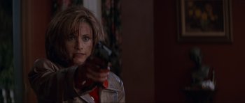 Movie still from “Scream” (1996), directed by Wes Craven – A woman is holding a gun in a room; Close Up shot, Low angle