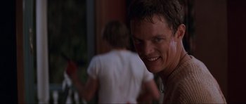 Movie still from “Scream” (1996), directed by Wes Craven – A person smiling with another person in the background; Close Up shot, Low angle