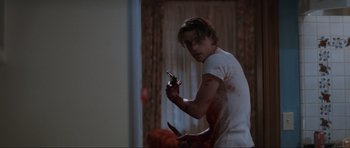 Movie still from “Scream” (1996), directed by Wes Craven – A young man holding a knife in a room; Medium shot, Low angle