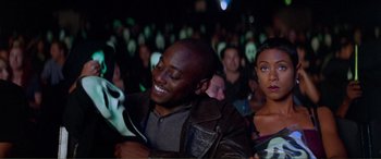 Movie still from “Scream 2” (1997), directed by Wes Craven – A group of people sitting in a room with masks on; Medium shot, Over the shoulder angle