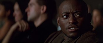 Movie still from “Scream 2” (1997), directed by Wes Craven – A man looking at the camera while another man looks on; Close Up shot, Low angle