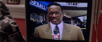 Movie still from “Scream 2” (1997), directed by Wes Craven – A man wearing a suit and tie on a tv screen; Close Up shot, Low angle