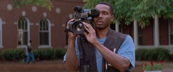 Movie still from “Scream 2” (1997), directed by Wes Craven – A man holding a video camera up to his face; Close Up shot, Low angle