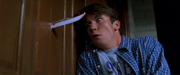 Movie still from “Scream 2” (1997), directed by Wes Craven – A young man holding a knife up to his head; Close Up shot, Low angle