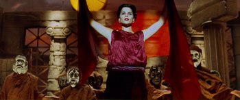 Movie still from “Scream 2” (1997), directed by Wes Craven – A woman standing in front of a group of masks; Medium shot, Low angle