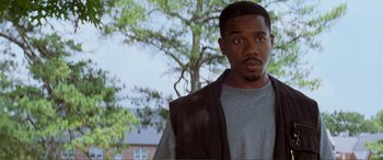 Movie still from “Scream 2” (1997), directed by Wes Craven – A man standing in front of a tree looking at the camera; Close Up shot, Low angle
