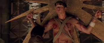 Movie still from “Scream 2” (1997), directed by Wes Craven – A shirtless man tied to a wooden pole; Medium shot, Low angle