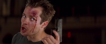 Movie still from “Scream 2” (1997), directed by Wes Craven – A person holding a gun with blood on his face; Close Up shot, Low angle