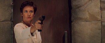 Movie still from “Scream 2” (1997), directed by Wes Craven – A man holding a gun in a room; Medium shot, Low angle