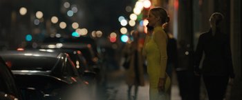 Movie still from “Scream VI” (2023), directed by Matt Bettinelli-Olpin – A woman in a yellow dress standing on the sidewalk; Medium shot, Over the shoulder angle
