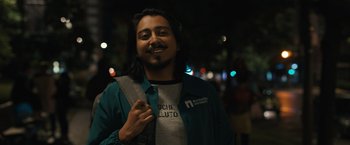 Movie still from “Scream VI” (2023), directed by Matt Bettinelli-Olpin – A man with long black hair is smiling for the camera; Medium shot, Low angle