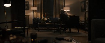 Movie still from “Scream VI” (2023), directed by Matt Bettinelli-Olpin – A man and a woman sitting on a couch in a living room; Wide shot, Over the shoulder angle