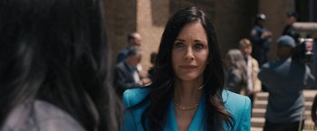 Movie still from “Scream VI” (2023), directed by Matt Bettinelli-Olpin – A woman in a blue suit looking at the camera; Close Up shot, Over the shoulder angle