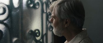 Movie still from “Scream VI” (2023), directed by Matt Bettinelli-Olpin – An older man with white hair looking out of a window; Close Up shot, Over the shoulder angle
