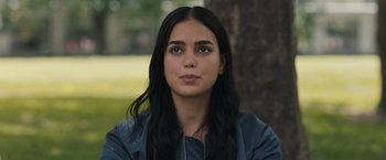 Movie still from “Scream VI” (2023), directed by Matt Bettinelli-Olpin – A woman with long black hair sitting in front of a tree; Close Up shot, Over the shoulder angle