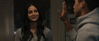 Movie still from “Scream VI” (2023), directed by Matt Bettinelli-Olpin – A young woman smiling at the camera while a man raises his hand; Close Up shot, Over the shoulder angle