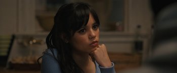 Movie still from “Scream VI” (2023), directed by Matt Bettinelli-Olpin – A woman sitting in front of a window with her hand under her chin; Close Up shot, High angle