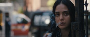 Movie still from “Scream VI” (2023), directed by Matt Bettinelli-Olpin – A woman is smoking a cigarette in the street; Close Up shot, Over the shoulder angle