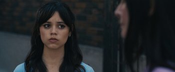 Movie still from “Scream VI” (2023), directed by Matt Bettinelli-Olpin – A young woman looking at the camera while standing in front of a man; Close Up shot, Over the shoulder angle