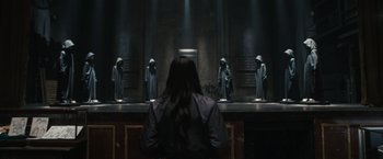 Movie still from “Scream VI” (2023), directed by Matt Bettinelli-Olpin – A woman is standing in front of a group of statues; Wide shot, Over the shoulder angle