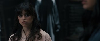 Movie still from “Scream VI” (2023), directed by Matt Bettinelli-Olpin – A woman with long dark brown hair wearing a pink shirt; Close Up shot, Over the shoulder angle