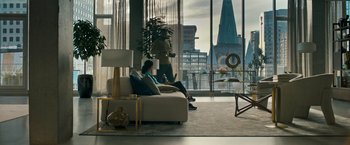 Movie still from “Scream VI” (2023), directed by Matt Bettinelli-Olpin – A woman sitting on top of a white couch in front of a window; Extreme Wide shot, Over the shoulder angle