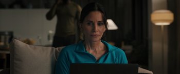 Movie still from “Scream VI” (2023), directed by Matt Bettinelli-Olpin – A woman sitting in front of a laptop computer; Close Up shot, Over the shoulder angle