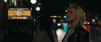 Movie still from “Scream VI” (2023), directed by Matt Bettinelli-Olpin – A woman standing on the side of the street at night; Close Up shot, Over the shoulder angle