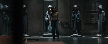 Movie still from “Scream VI” (2023), directed by Matt Bettinelli-Olpin – A woman standing in front of a wall with graffiti on it; Wide shot, Over the shoulder angle