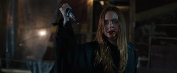 Movie still from “Scream VI” (2023), directed by Matt Bettinelli-Olpin – A woman with blood on her face holding a knife in her hand; Close Up shot, Over the shoulder angle