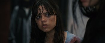 Movie still from “Scream VI” (2023), directed by Matt Bettinelli-Olpin – A young woman with a bruised face stares into the camera; Close Up shot, Over the shoulder angle
