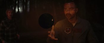 Movie still from “Secret Headquarters” (2022), directed by Henry Joost – A man holding a black ball in his hand; Medium shot, Low angle