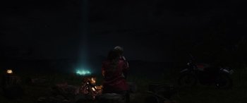 Movie still from “Secret Headquarters” (2022), directed by Henry Joost – A woman sitting in front of a campfire at night; Extreme Wide shot, Over the shoulder angle