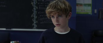 Movie still from “Secret Headquarters” (2022), directed by Henry Joost – A young boy with blonde hair and blue eyes stares into the camera; Close Up shot, Over the shoulder angle