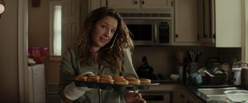 Movie still from “Secret Headquarters” (2022), directed by Henry Joost – A woman holding a tray of donuts while talking on a phone; Close Up shot, Low angle