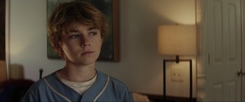 Movie still from “Secret Headquarters” (2022), directed by Henry Joost – A young man in a blue shirt is looking at the camera; Close Up shot, Over the shoulder angle