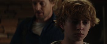 Movie still from “Secret Headquarters” (2022), directed by Henry Joost – A man and a boy are sitting in a dark room; Close Up shot, Over the shoulder angle