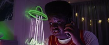 Movie still from “Secret Headquarters” (2022), directed by Henry Joost – A young man talking on a cell phone in front of a neon sign; Close Up shot, Low angle