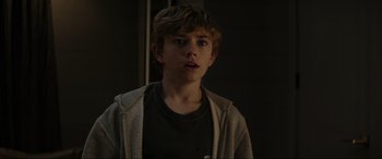 Movie still from “Secret Headquarters” (2022), directed by Henry Joost – A young boy is standing in a dark room; Close Up shot, Over the shoulder angle