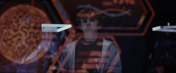 Movie still from “Secret Headquarters” (2022), directed by Henry Joost – A young man is standing in front of a blurry background; Close Up shot, Over the shoulder angle