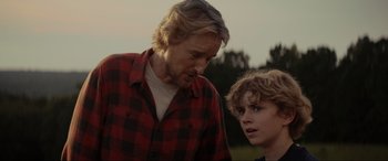 Movie still from “Secret Headquarters” (2022), directed by Henry Joost – A man standing next to a boy in a plaid shirt; Close Up shot, Over the shoulder angle