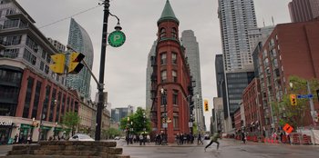 Movie still from “Secret Society of Second Born Royals” (2020), directed by Anna Mastro – A group of people walking down a street near tall buildings; Extreme Wide shot, Low angle