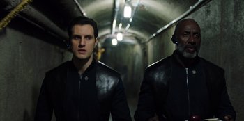 Movie still from “Secret Society of Second Born Royals” (2020), directed by Anna Mastro – Two men in leather jackets walking in an underground tunnel; Medium shot, Low angle